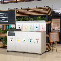 Mueble papelera Mallorca para interior instalado en una zona de comidas con recogida selectiva de residuos